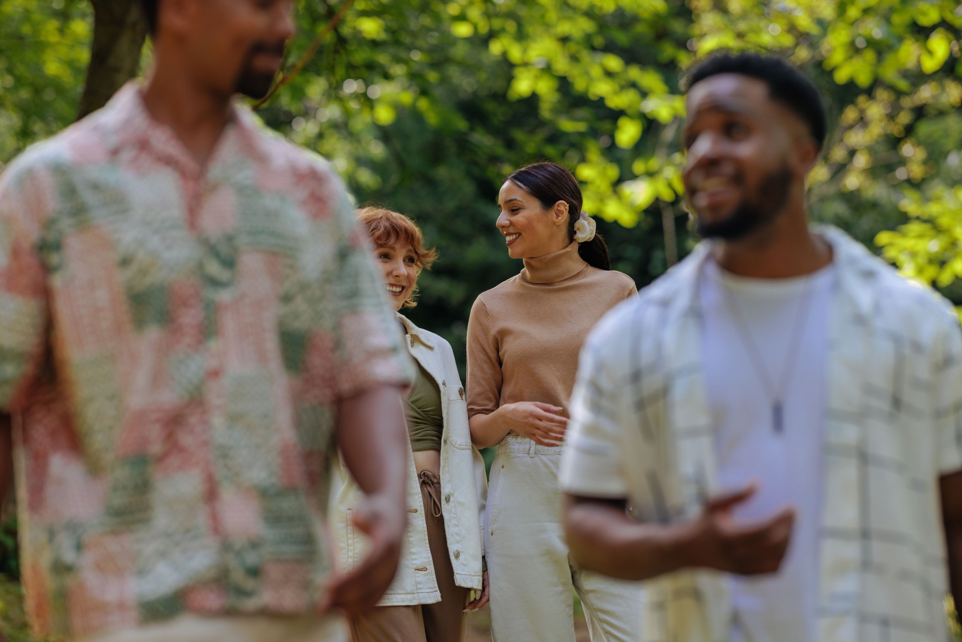 Four people walking through a park on a summer day
